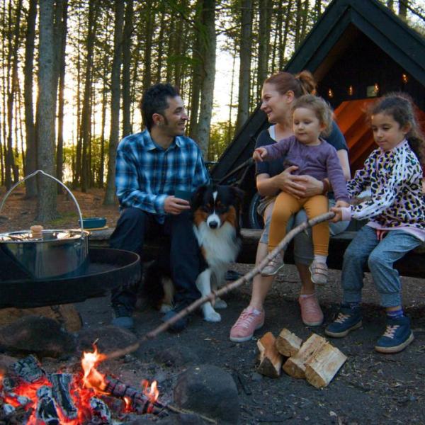 Parents and children enjoy the fire at a shelter site and cook over the fire