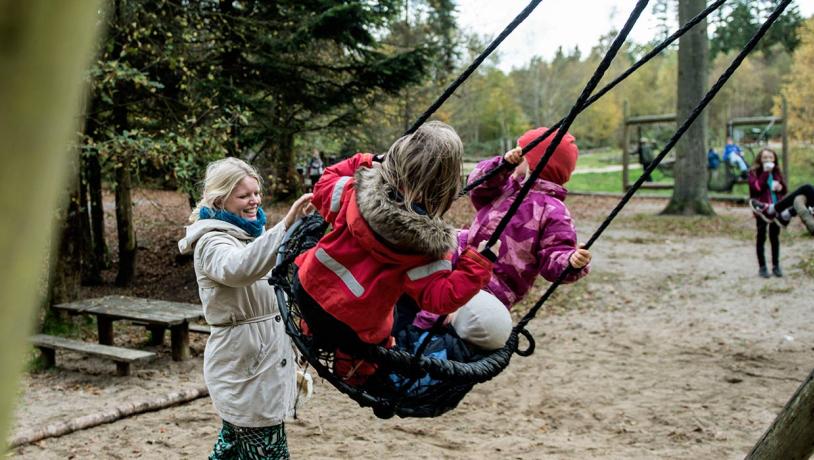 Children on swings at the forest playground in Sønderskoven in Vejle