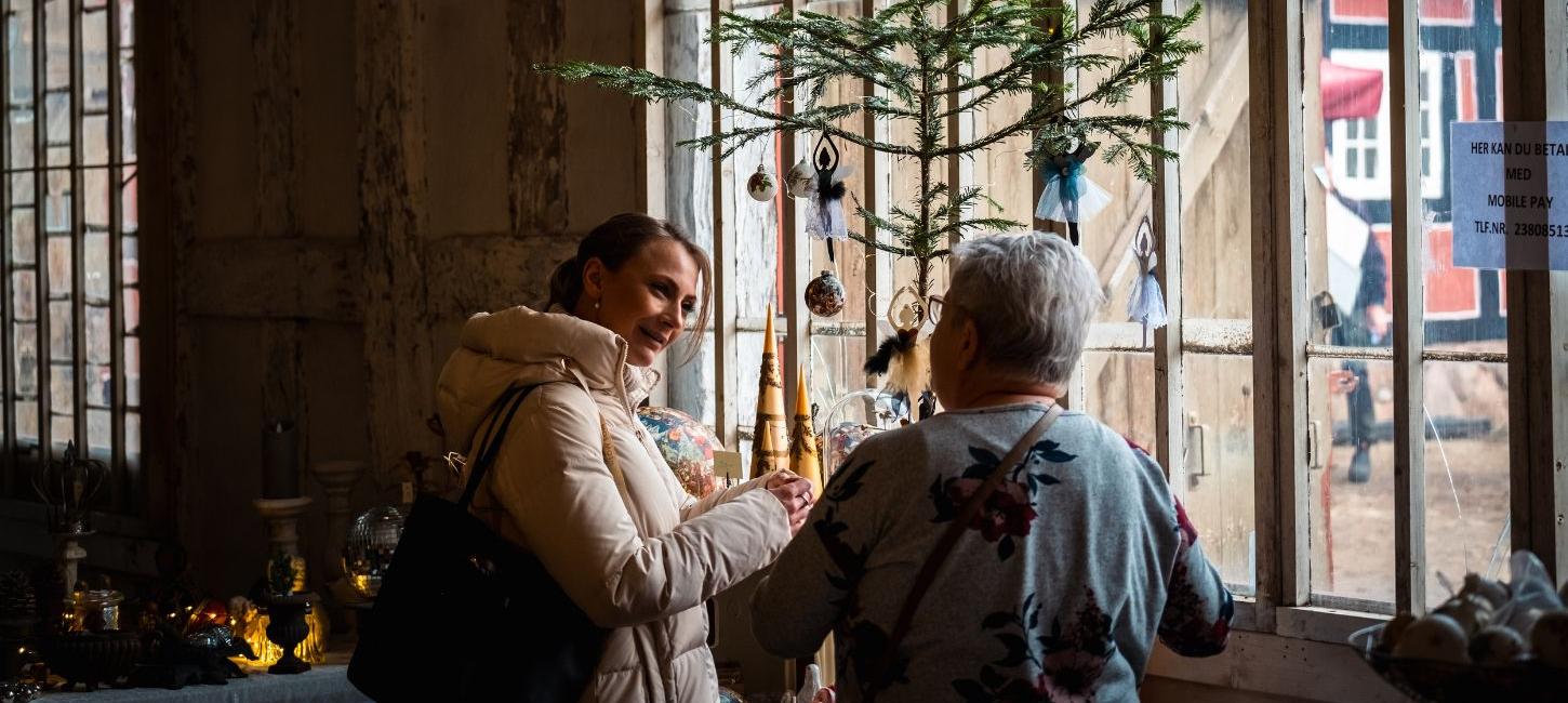 Two people look at stalls at the Christmas market at Tirsbæk Manor