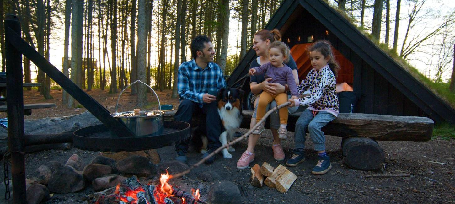 Parents and children enjoy the fire at a shelter site and cook over the fire