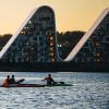 People in kayaks on Vejle Fjord with Bølgen (the Wave) in the background