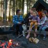 Parents and children enjoy the fire at a shelter site and cook over the fire