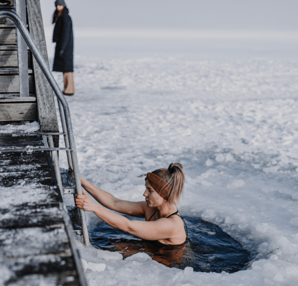 Woman bathing in winter by the fjord with ice on the fjord