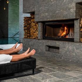 Couple in front of the fireplace with wine at Hotel Vejlefjord